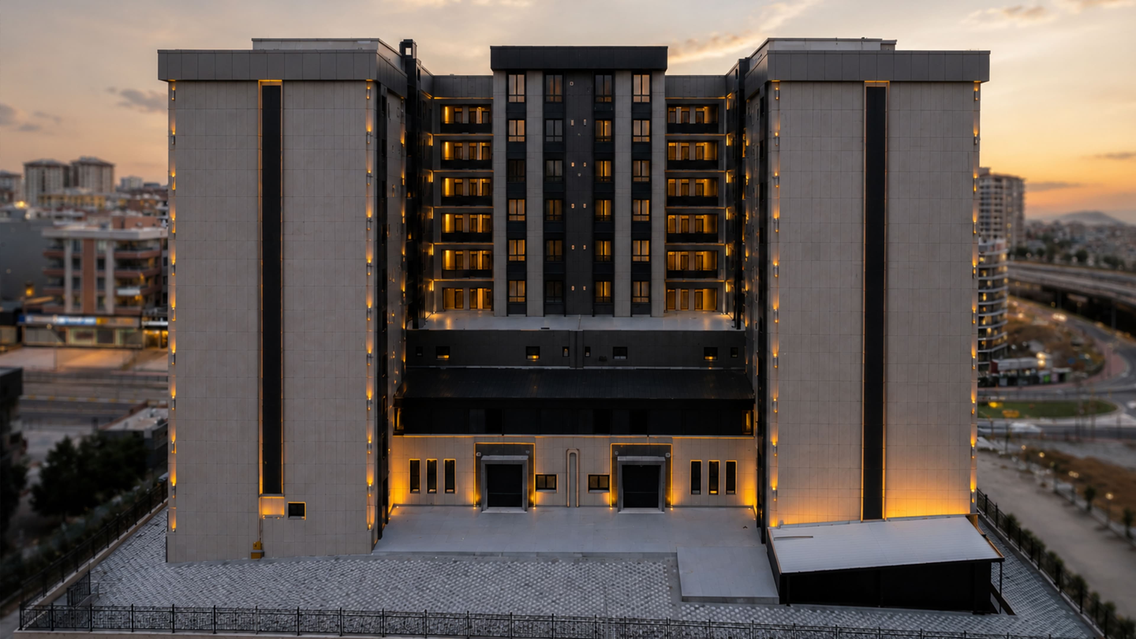 Merit Park'ın U planlı antrasit cepheli konut bloğunun görselleştirmesi; yanında viyadük, çevresinde yeşil peyzaj ve yoğun şehir dokusu