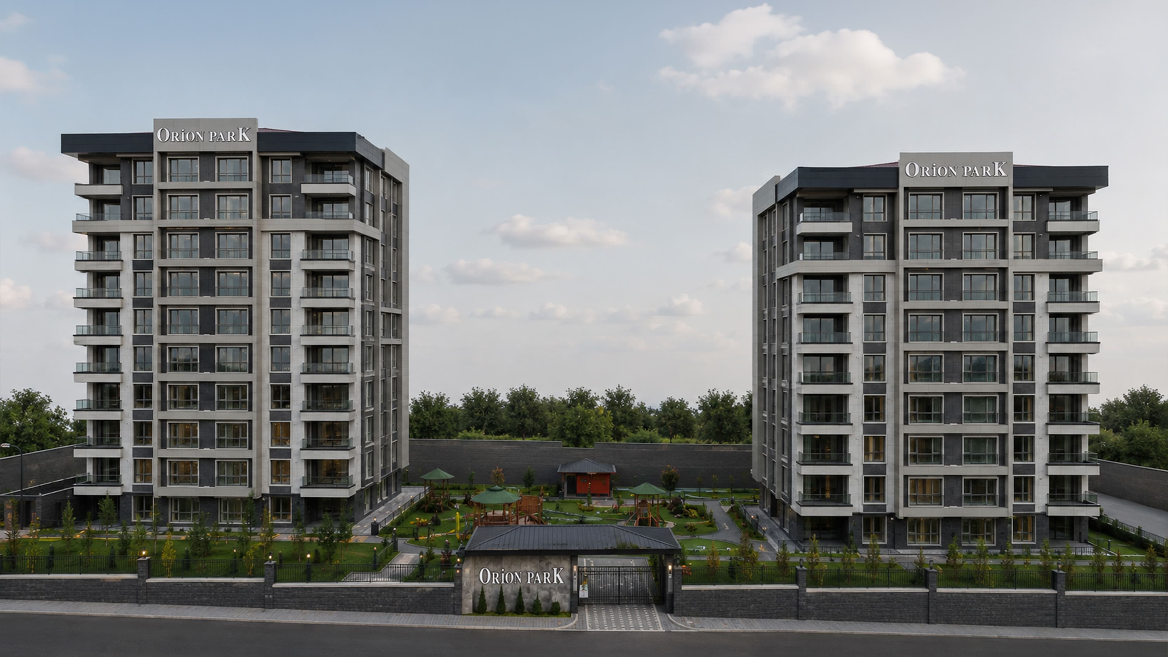 Orion Park'ın havadan görünümü; blokların solunda çiçekli yeşil park, önünde yol, avlusunda çocuk oyun alanı ve düzenlenmiş peyzaj